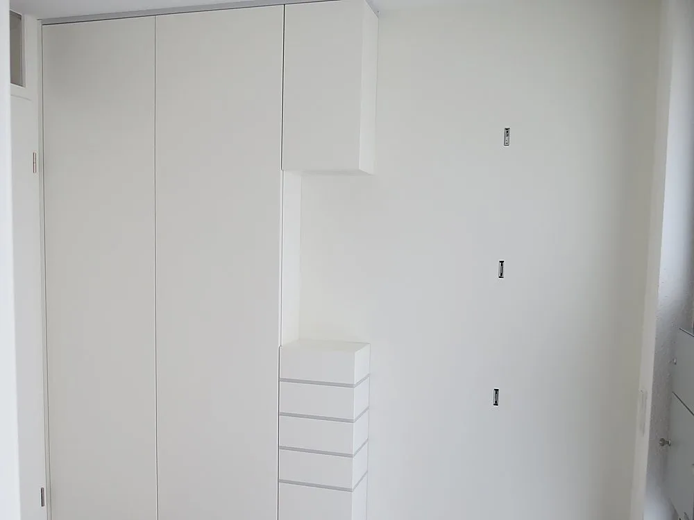 Weiße Garderobe mit Schubladen und offenen Fächern bei Tageslicht – Schreinerei Hübl