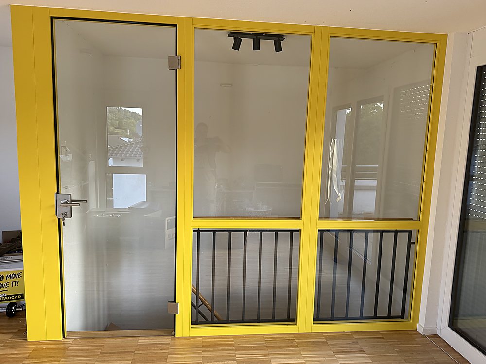 Gelbe Glas-Trennwand mit Tür als Raumteiler – Sonderanfertigung der Schreinerei Hübl Schorndorf