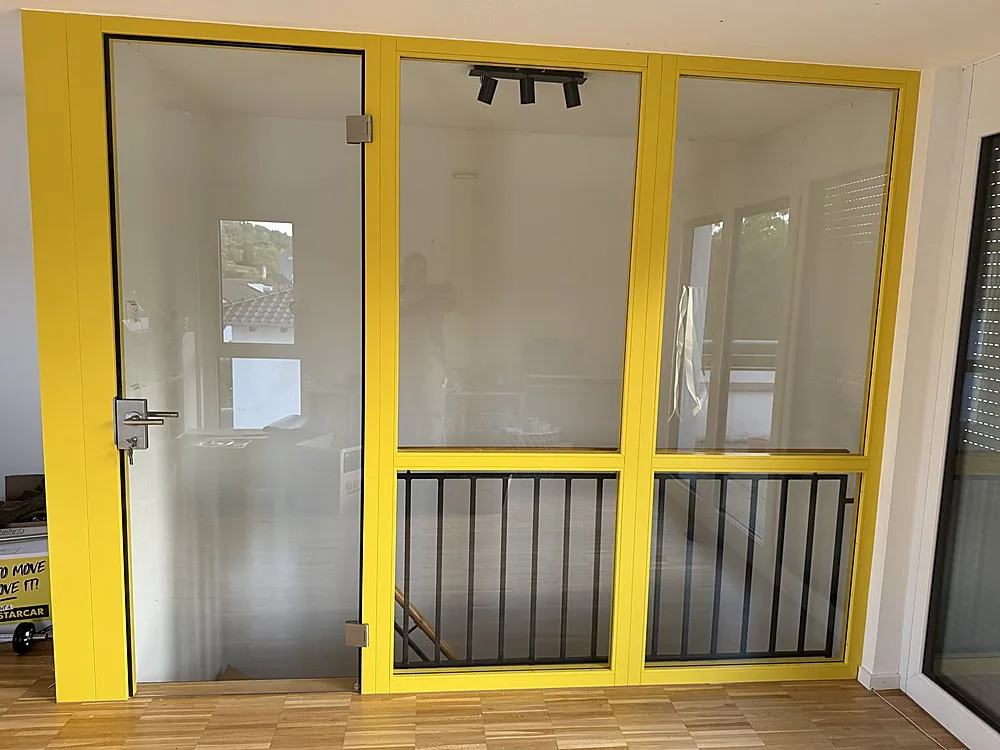 Gelbe Glas-Trennwand mit Tür als Raumteiler – Sonderanfertigung der Schreinerei Hübl Schorndorf