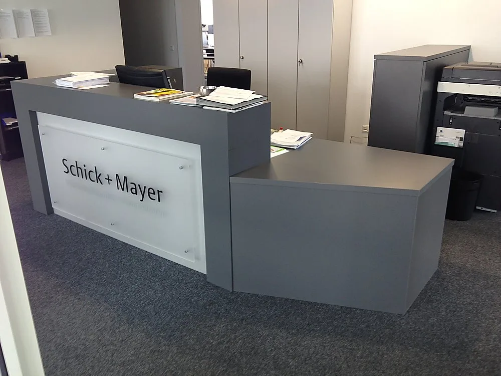 Graue Empfangstheke mit Firmenlogo im Büro – Schreinerei Hübl Schorndorf